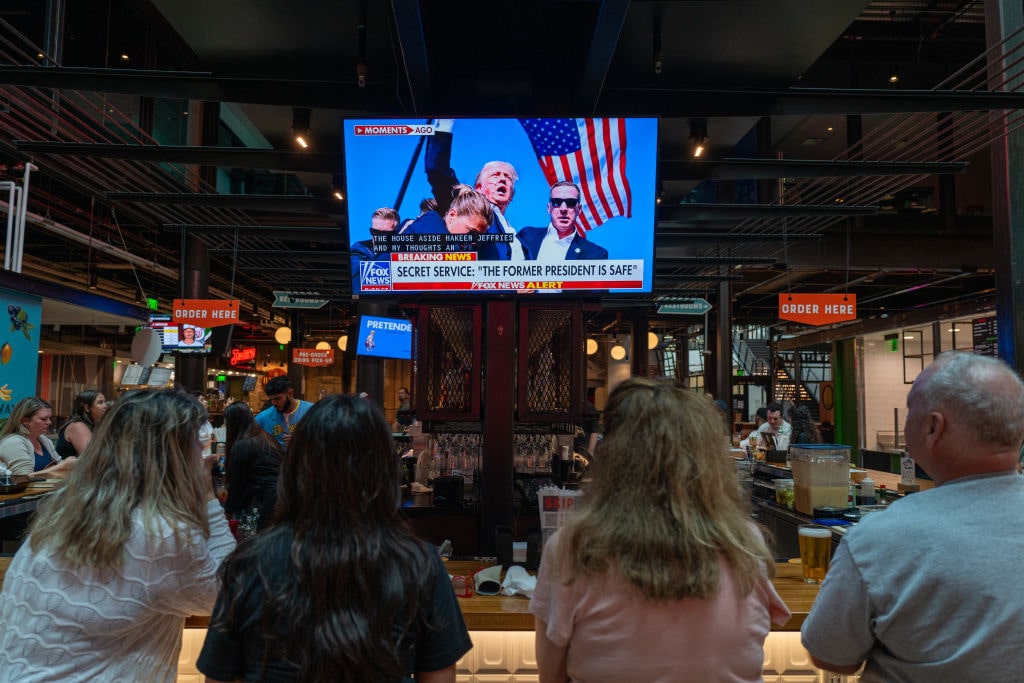 Americans React To Possible Trump Assassination AttemptMILWAUKEE, WISCONSIN - JULY 13: People watch television news at a bar in Milwaukee displaying images from a campaign rally for former U.S. President Donald Trump where he was apparently injured on July 13, 2024 in Milwaukee, Wisconsin. Details are unclear, but Secret Service quickly ushered Trump away while speaking at the Pennsylvania rally. (Photo by Spencer Platt/Getty Images)